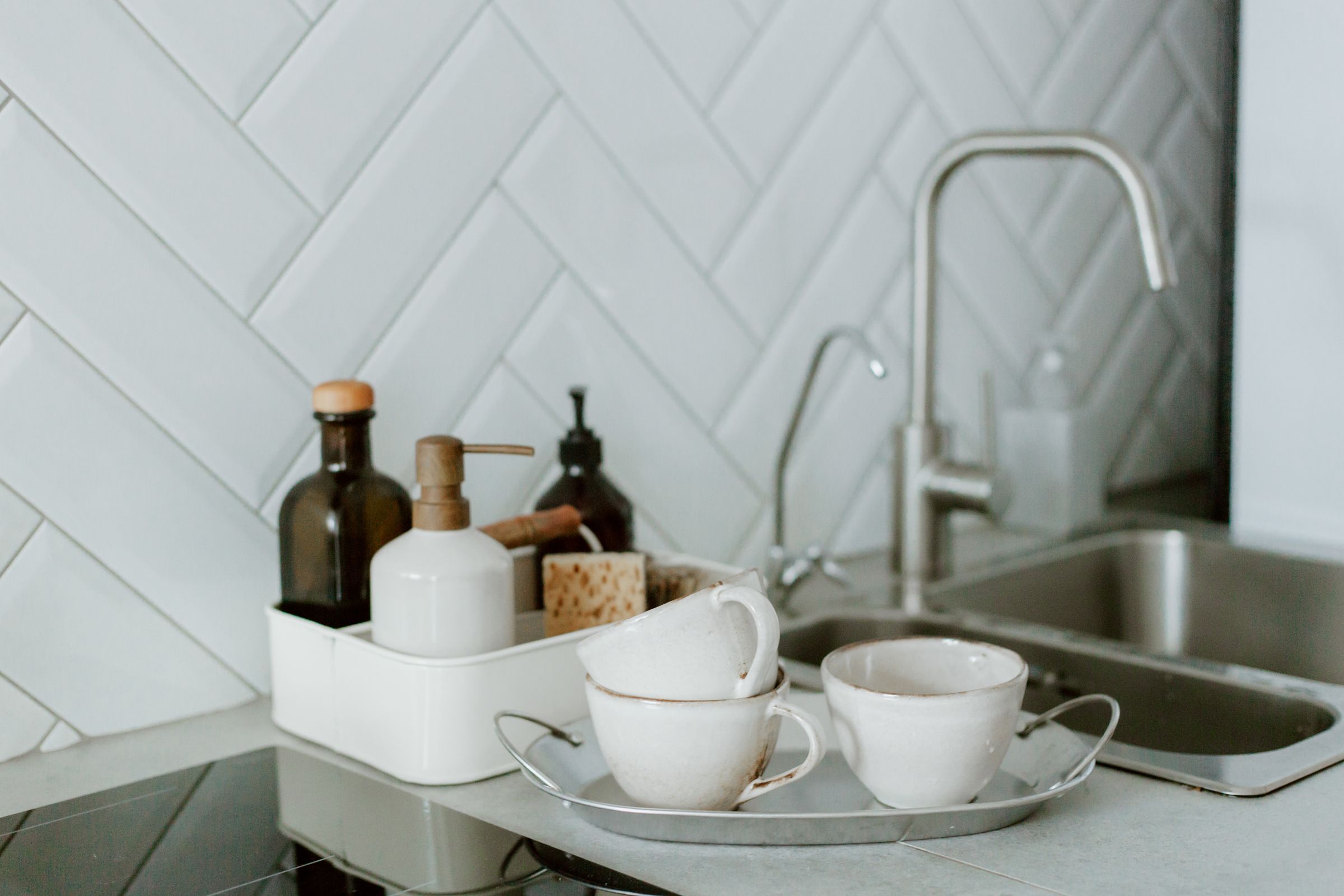 Tidy kitchen counter with cups, soap dispensers and a sink